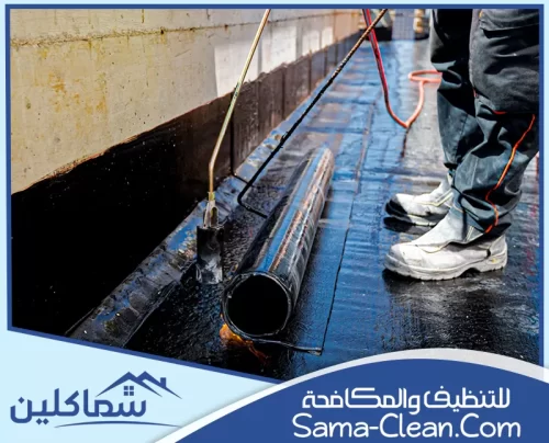 عامل يستخدم النار لتثبيت لفائف العزل المائي على سطح المبنى لحمايته من تسرب المياه والرطوبة.