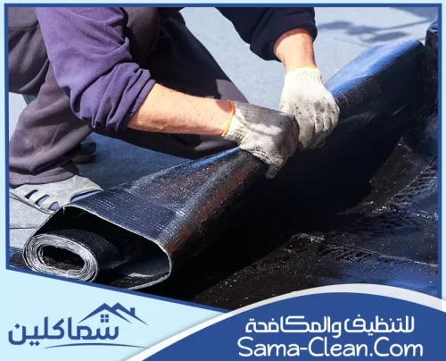 عامل يثبت لفائف العزل الحراري على السطح بعناية لحماية المبنى من تسرب المياه والحرارة.